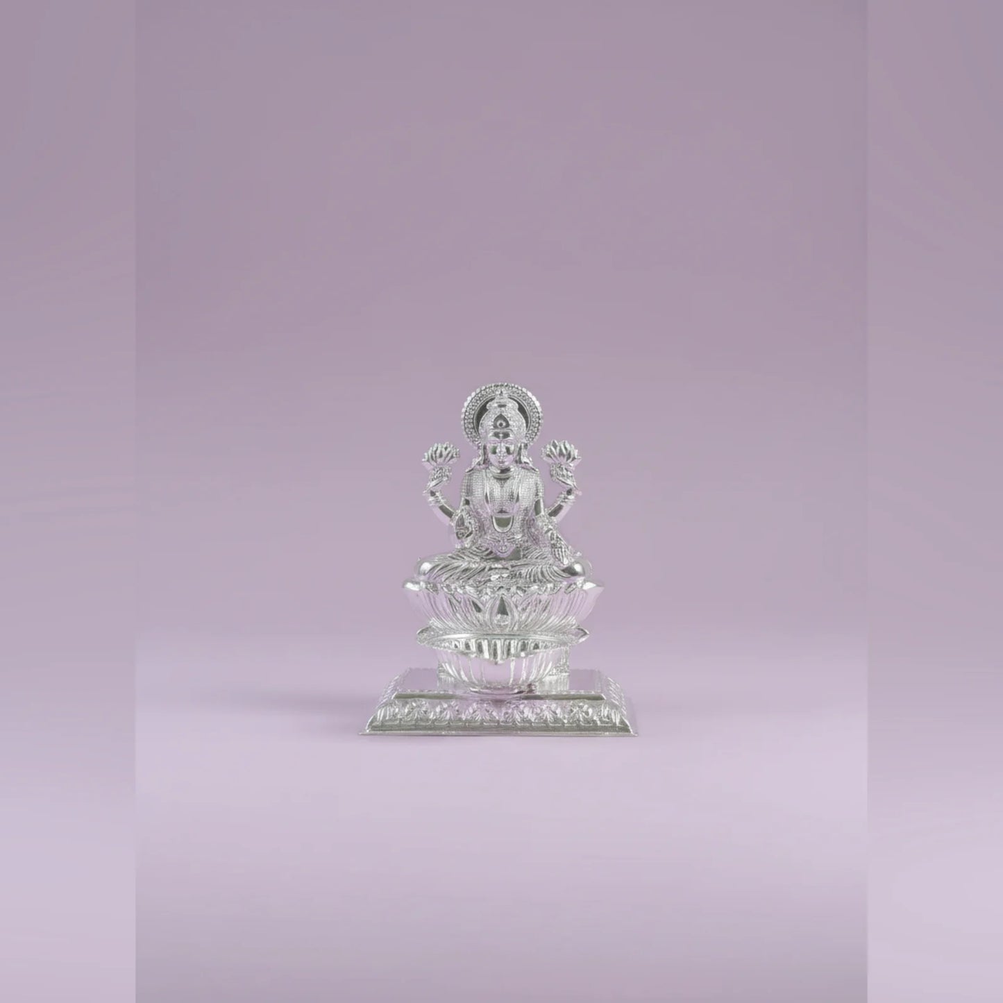 Silver statue of a seated figure on a light purple background