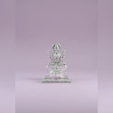 Silver statue of a seated figure on a light purple background