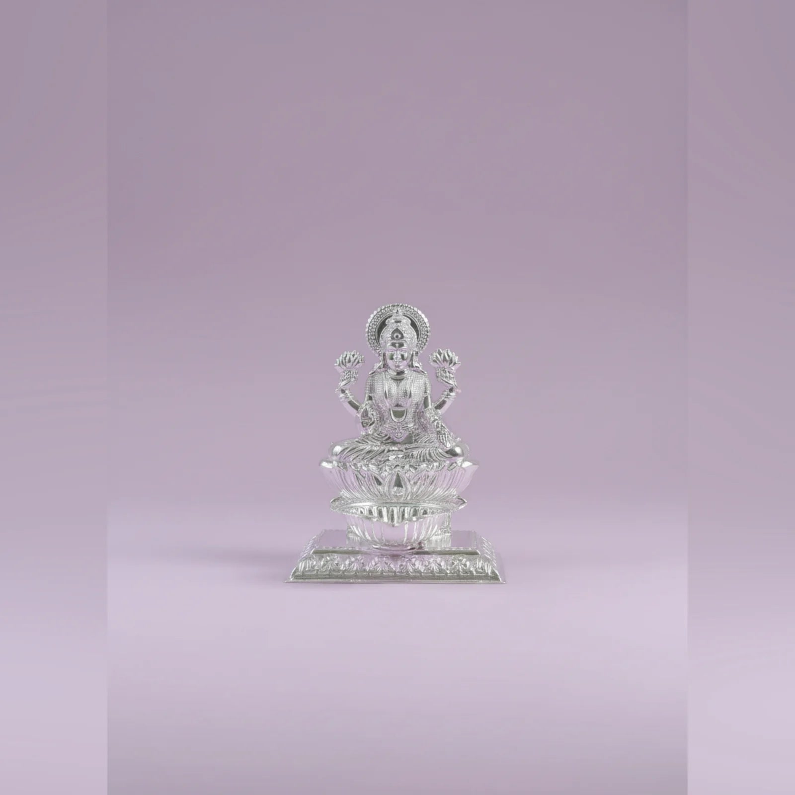 Silver statue of a seated figure on a light purple background