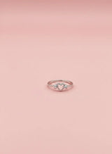 Rose gold ring with a diamond on a pink background