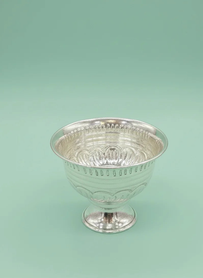 Silver cup with intricate design on a light green background