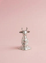 Silver cow-shaped object on a pink background