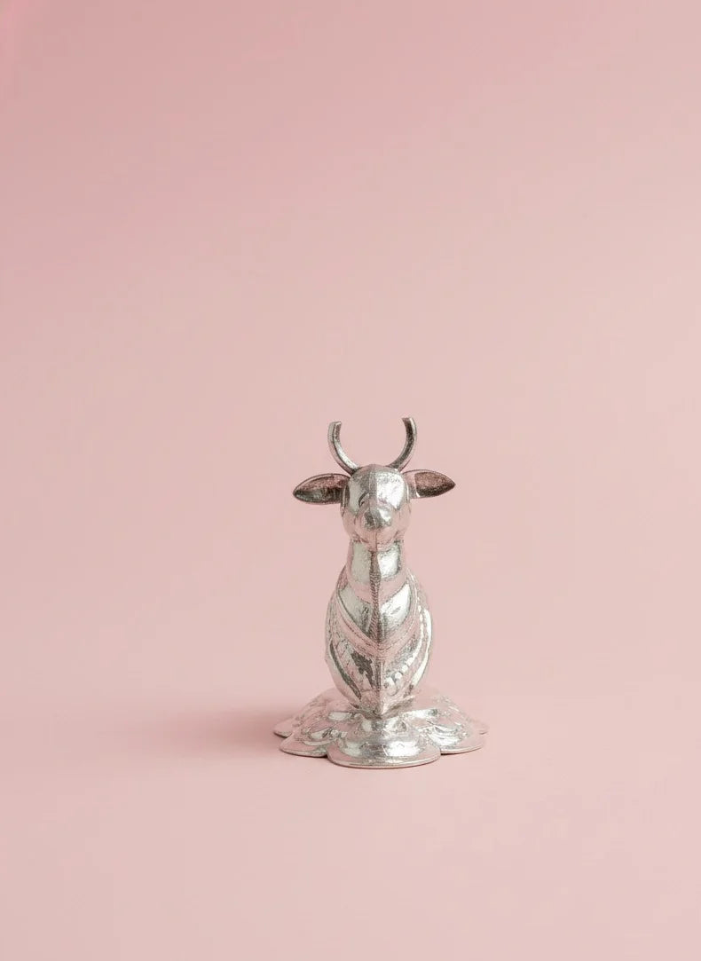 Silver cow-shaped object on a pink background