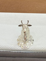Silver cow figurine on a textured white surface with a brown background