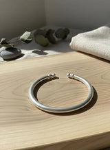 Silver bracelet on a wooden surface with a neutral background