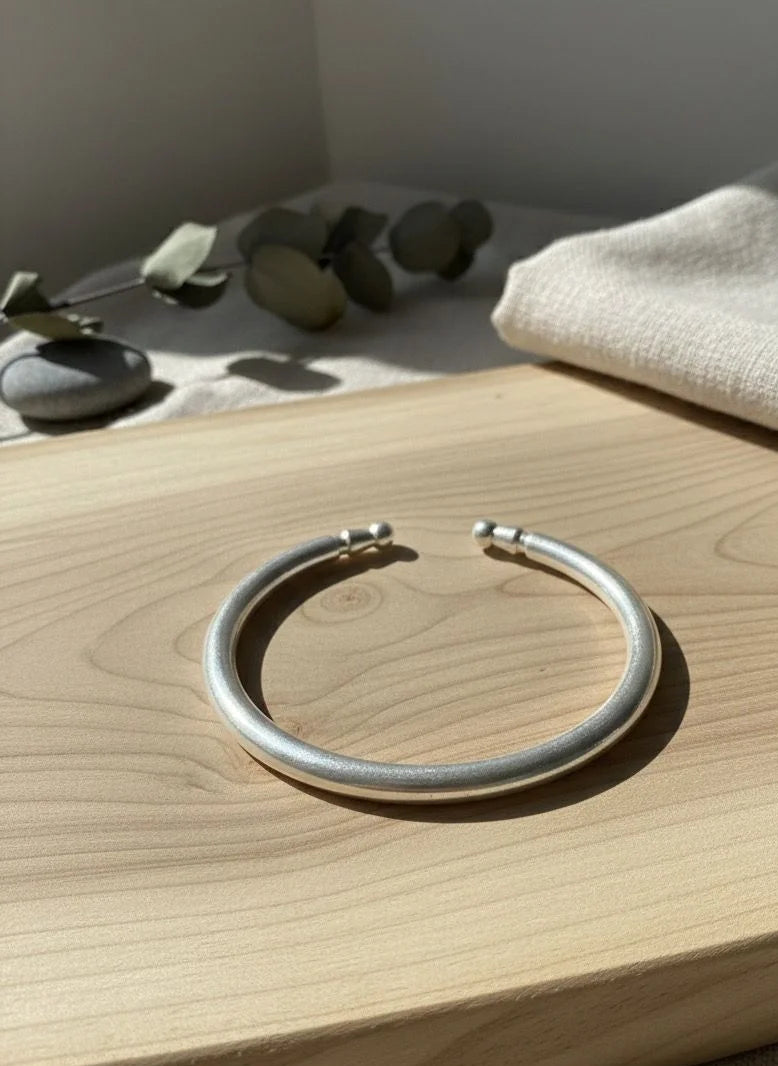 Silver bracelet on a wooden surface with a neutral background