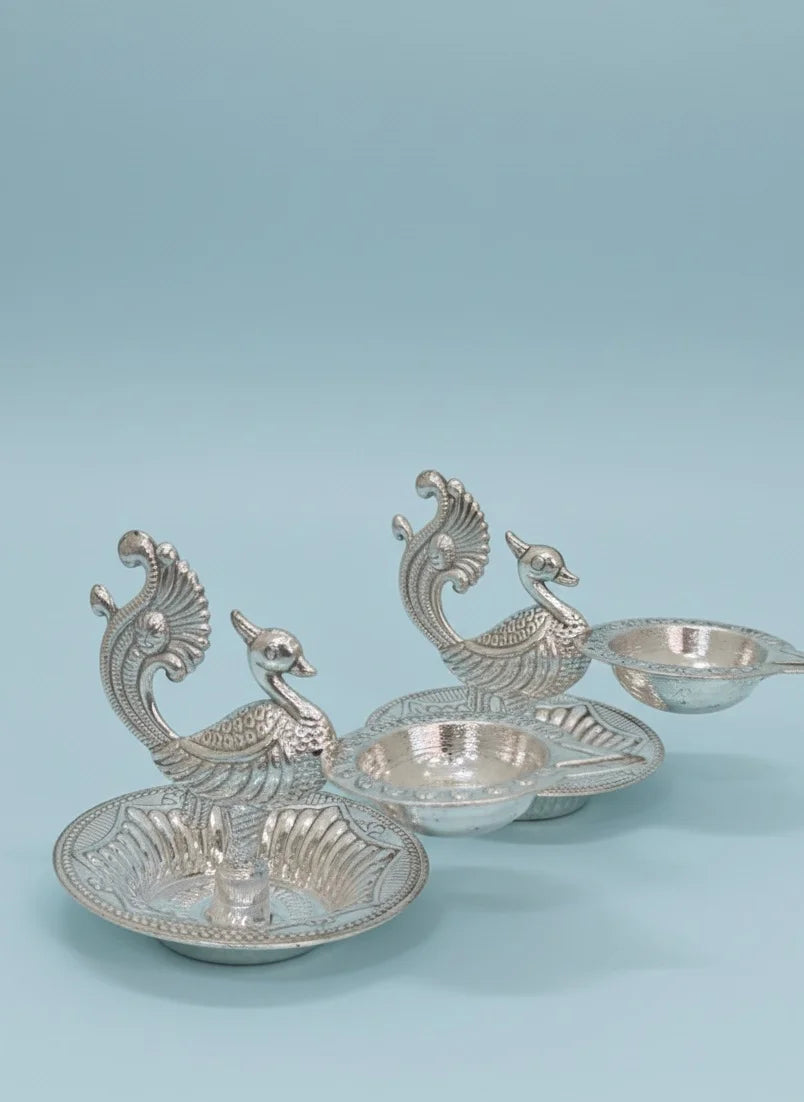Set of three silver peacock-shaped bowls on a light blue background