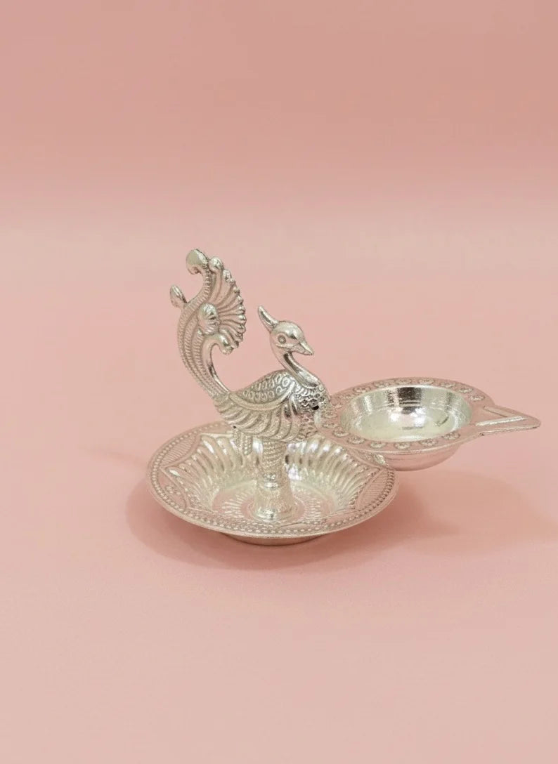 Decorative silver peacock-shaped dish on a pink background