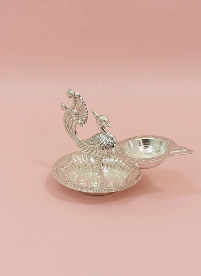 Decorative silver peacock-shaped dish on a pink background
