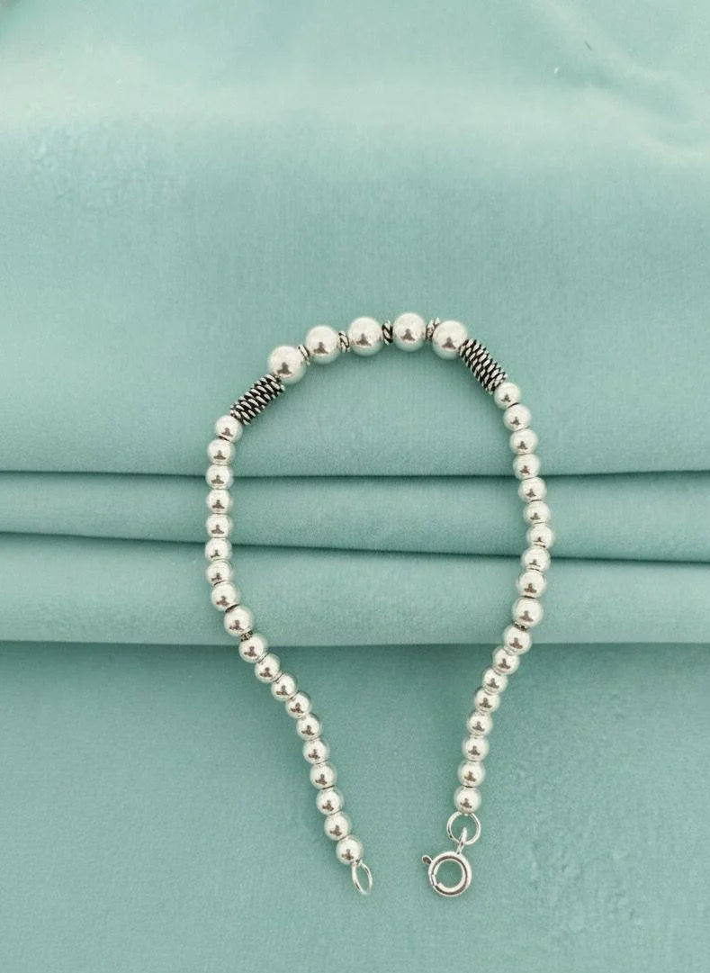 Silver ball bracelet on a light blue fabric background