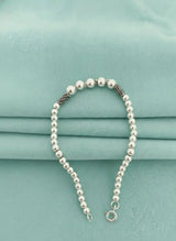 Silver ball bracelet on a light blue fabric background