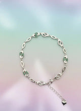 Silver bracelet with green gemstones on a gradient background
