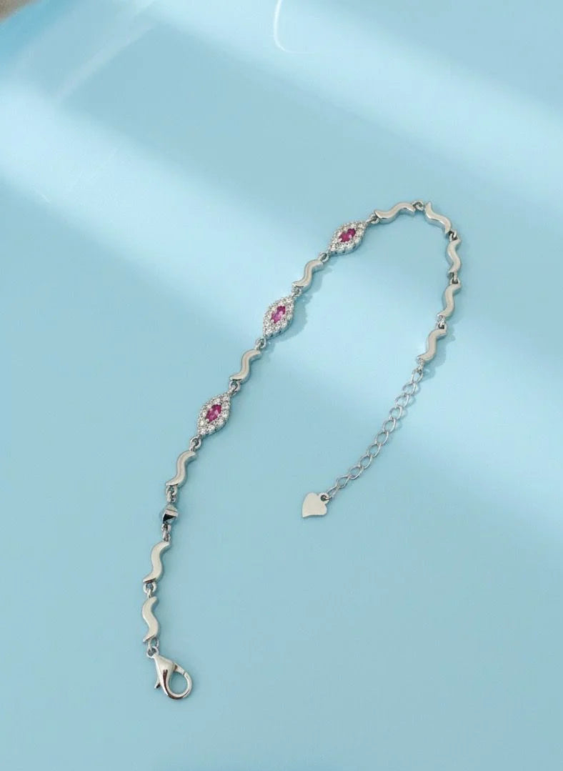 Silver bracelet with pink floral designs on a light blue background
