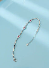 Silver bracelet with pink floral designs on a light blue background