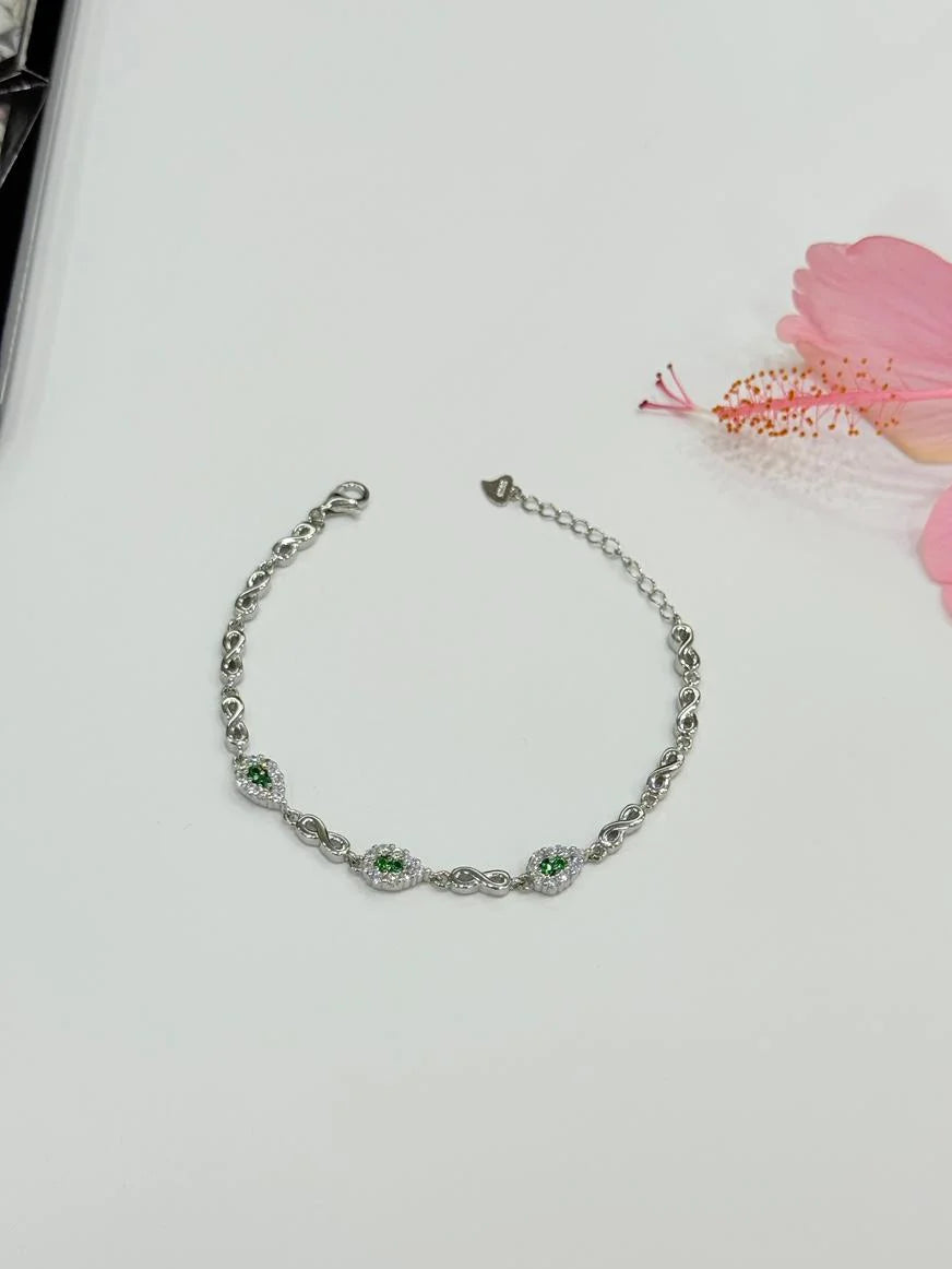 Silver bracelet with green gemstones on a light background