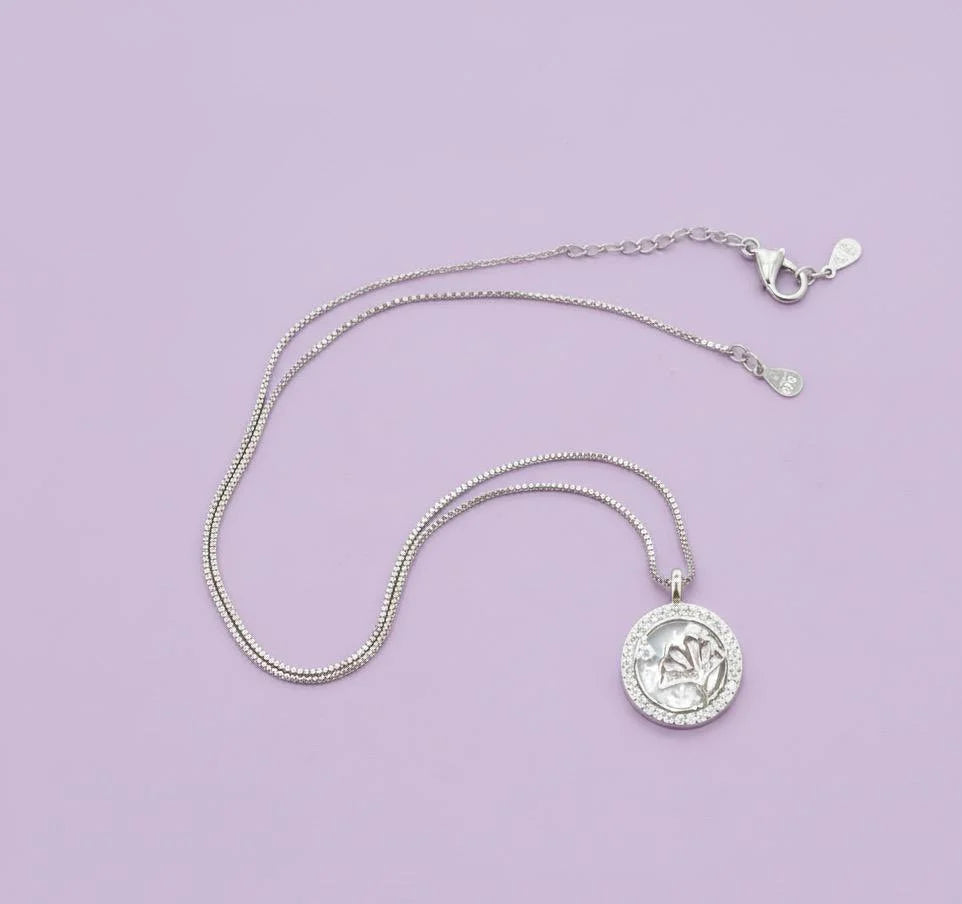 Silver necklace with a pendant on a light purple background