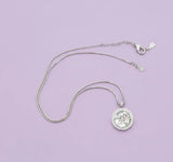 Silver necklace with a pendant on a light purple background