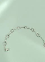 Silver bracelet with circular links on a light green background