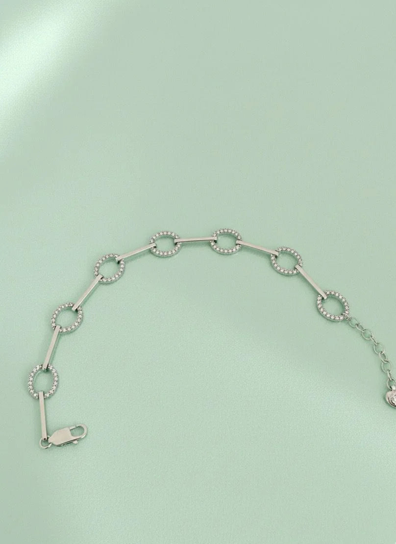 Silver bracelet with circular links on a light green background