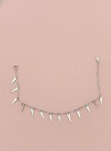 Silver bracelet with spike-like drops on a pink background