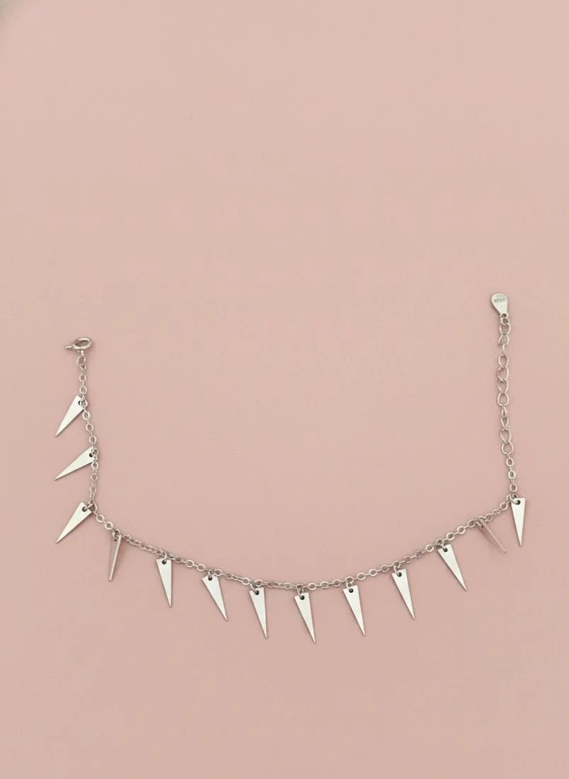 Silver bracelet with spike-like drops on a pink background