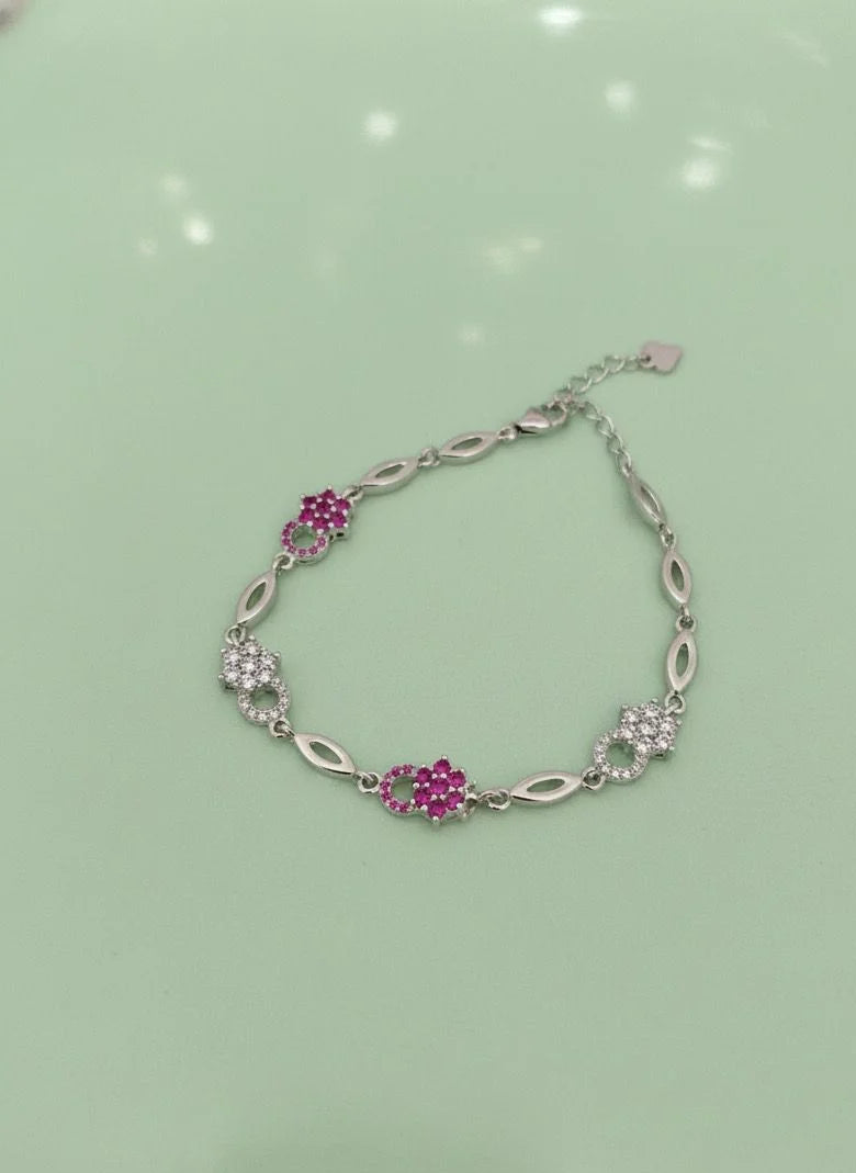 Silver bracelet with pink gemstones on a light green background
