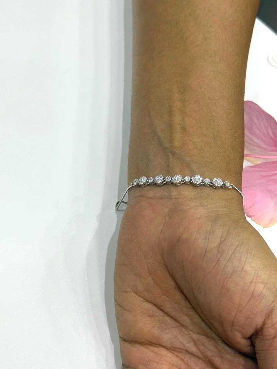 Silver bracelet on a wrist with a white background