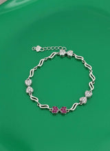 Silver bracelet with pink flowers on a green background
