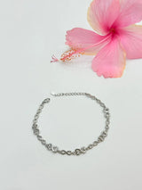 Silver chain bracelet on a light gray background with a pink flower.