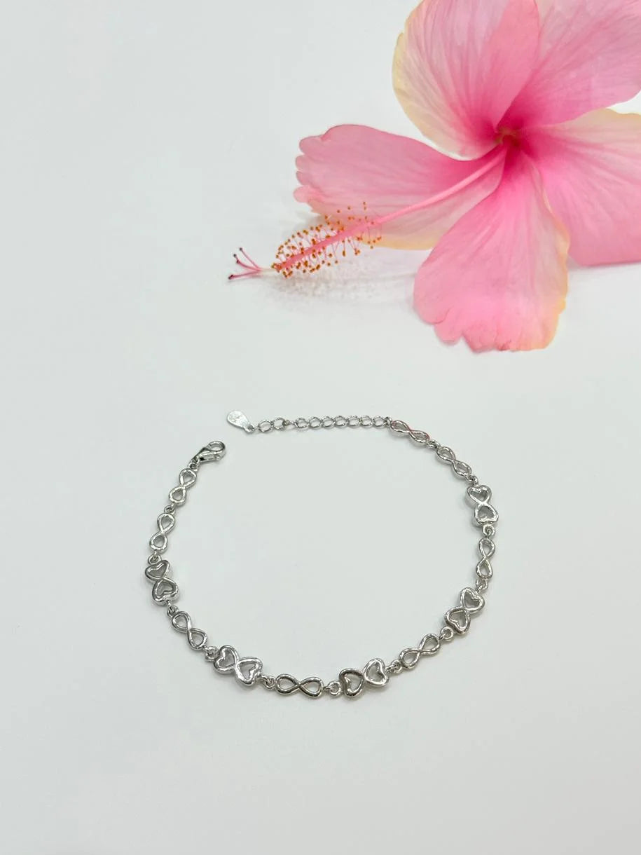 Silver chain bracelet on a light gray background with a pink flower.