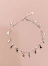 Silver bracelet with lightning-shaped charms on a pink background