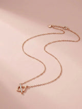 Rose gold necklace with a pendant on a pink background