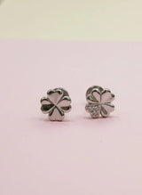 Silver four-leaf clover earrings on a pink background