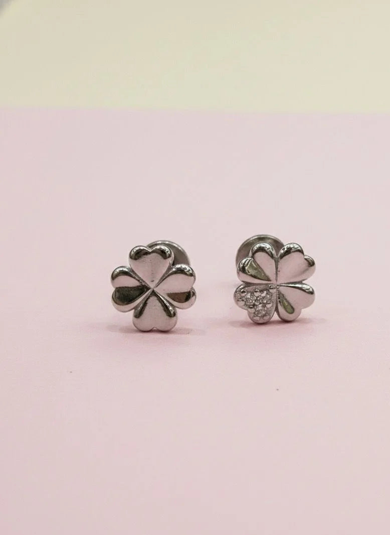 Silver four-leaf clover earrings on a pink background