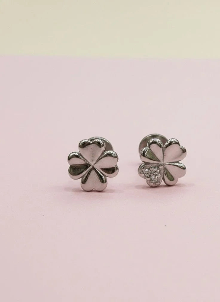 Silver four-leaf clover earrings on a pink background
