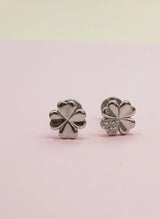 Silver four-leaf clover earrings on a pink background