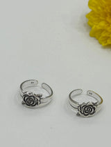 Two silver toe ring openers with rose designs on a white background with a yellow flower.