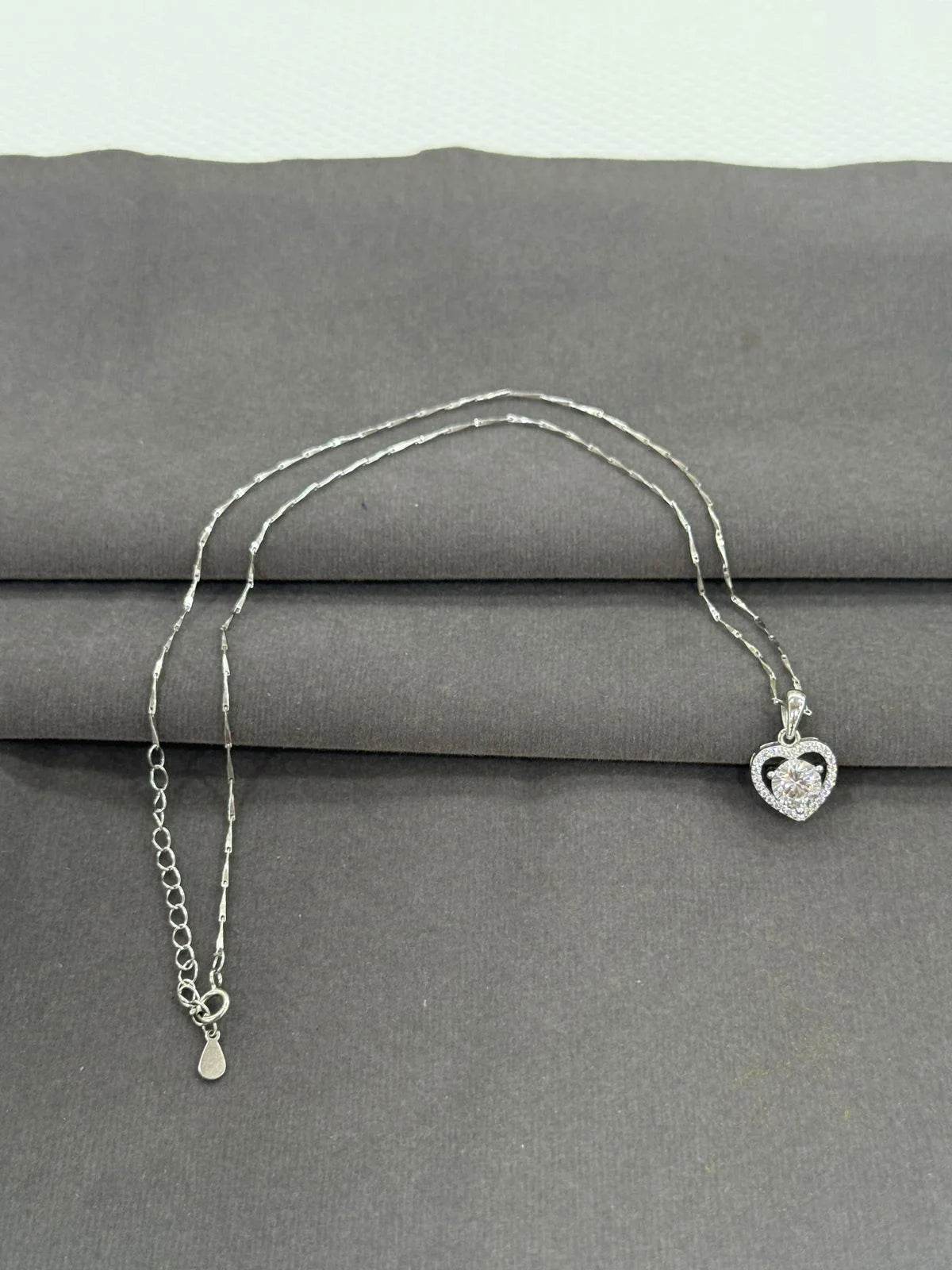 Silver necklace with a heart-shaped pendant on a gray surface