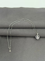 Silver necklace with a heart-shaped pendant on a gray surface