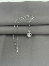 Silver necklace with a heart-shaped pendant on a gray surface