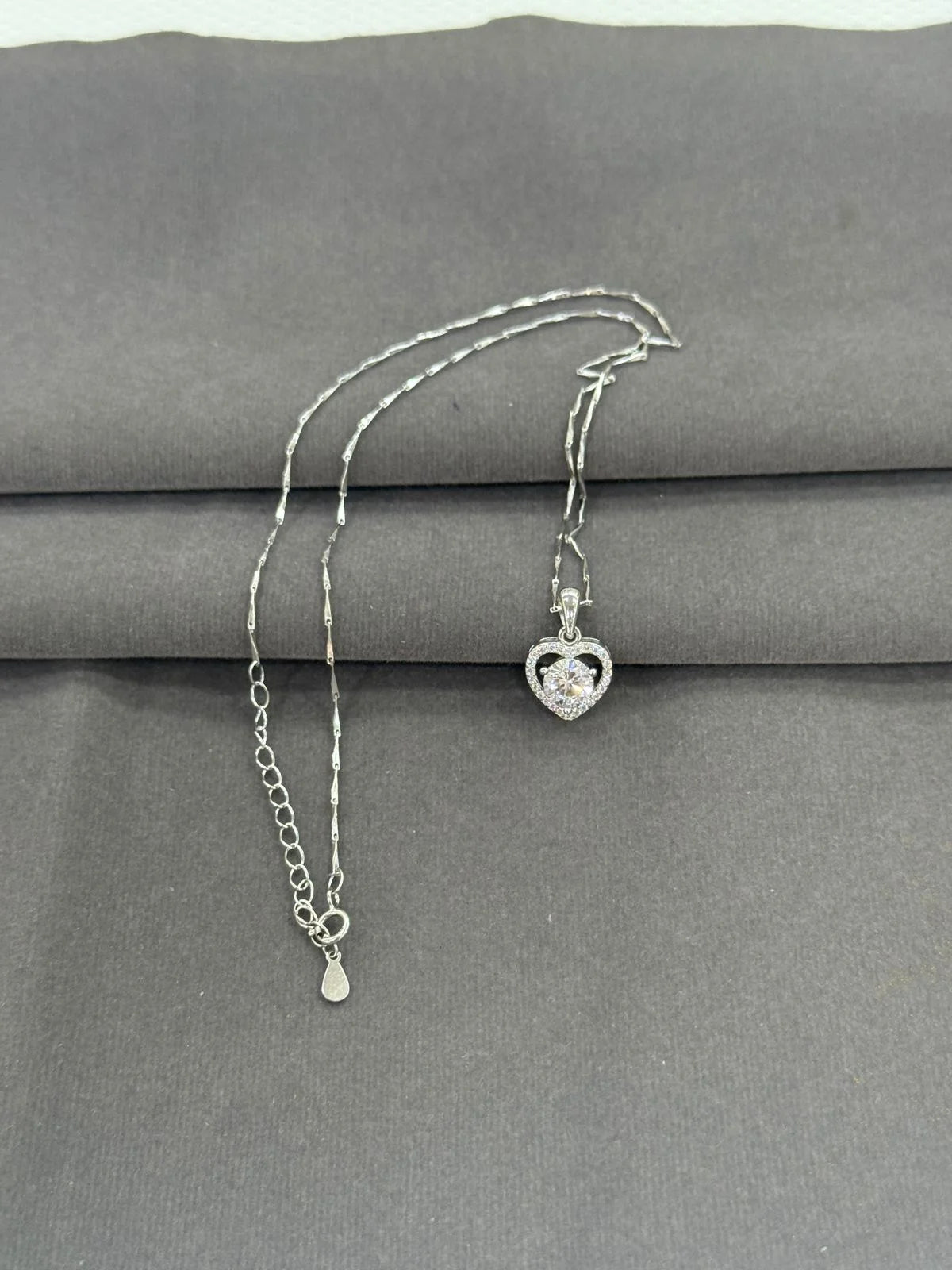 Silver necklace with a heart-shaped pendant on a gray surface