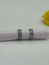 Decorative silver toe rings on a white cylindrical object with a yellow flower in the background