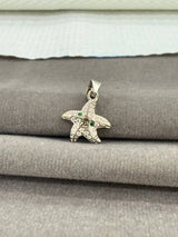 Starfish-shaped pendant with green stones on a textured surface