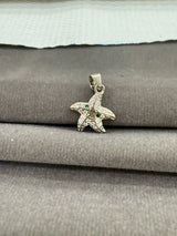 Starfish-shaped pendant with green stones on a textured surface
