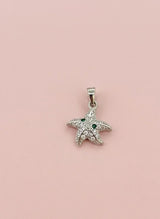 Starfish-shaped pendant with green stones on a pink background