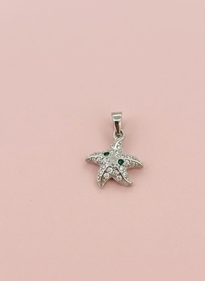 Starfish-shaped pendant with green stones on a pink background