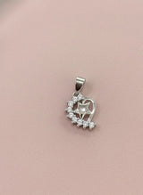 Silver heart-shaped pendant with clear stones on a pink background