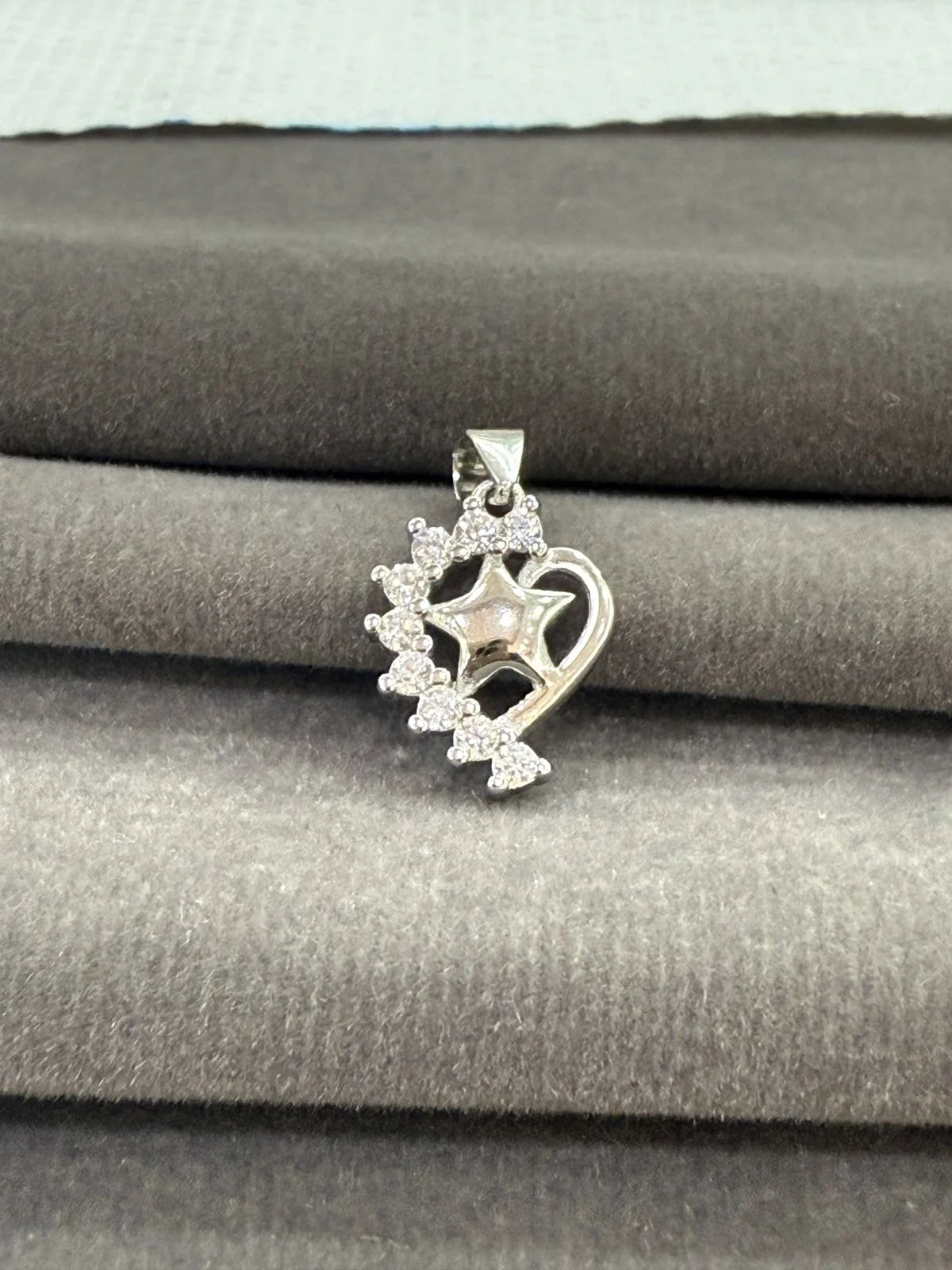 Silver pendant with star design on a gray fabric background