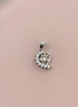 Silver heart-shaped pendant with clear stones on a pink background