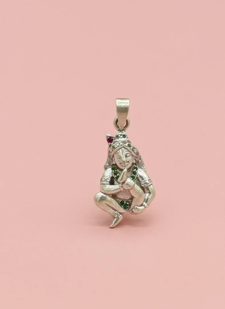 Silver pendant of a woman with gemstones on a pink background
